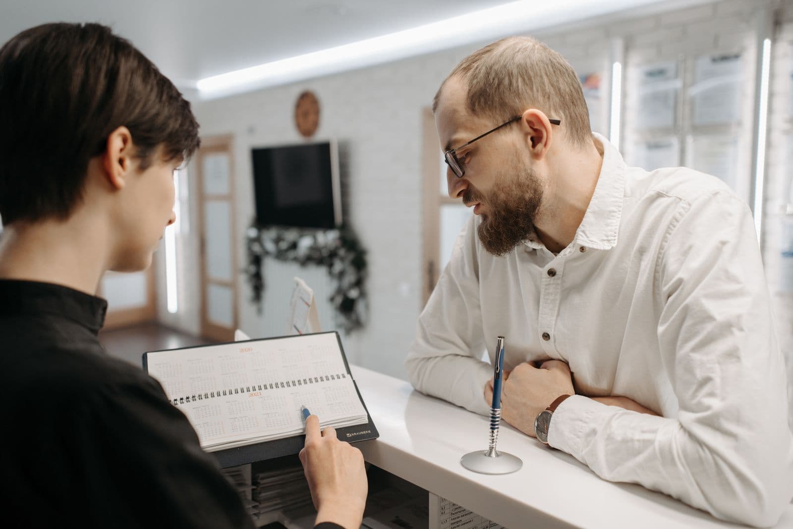 Receptionist booking an appointment with a client over a calendar