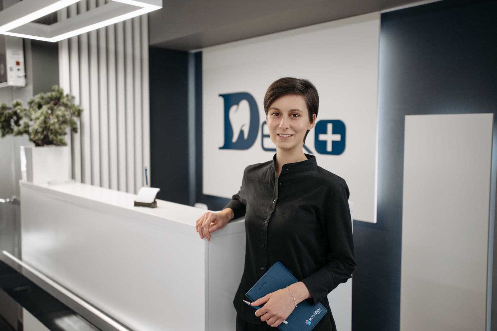 Receptionist smiling at a modern clinic front desk