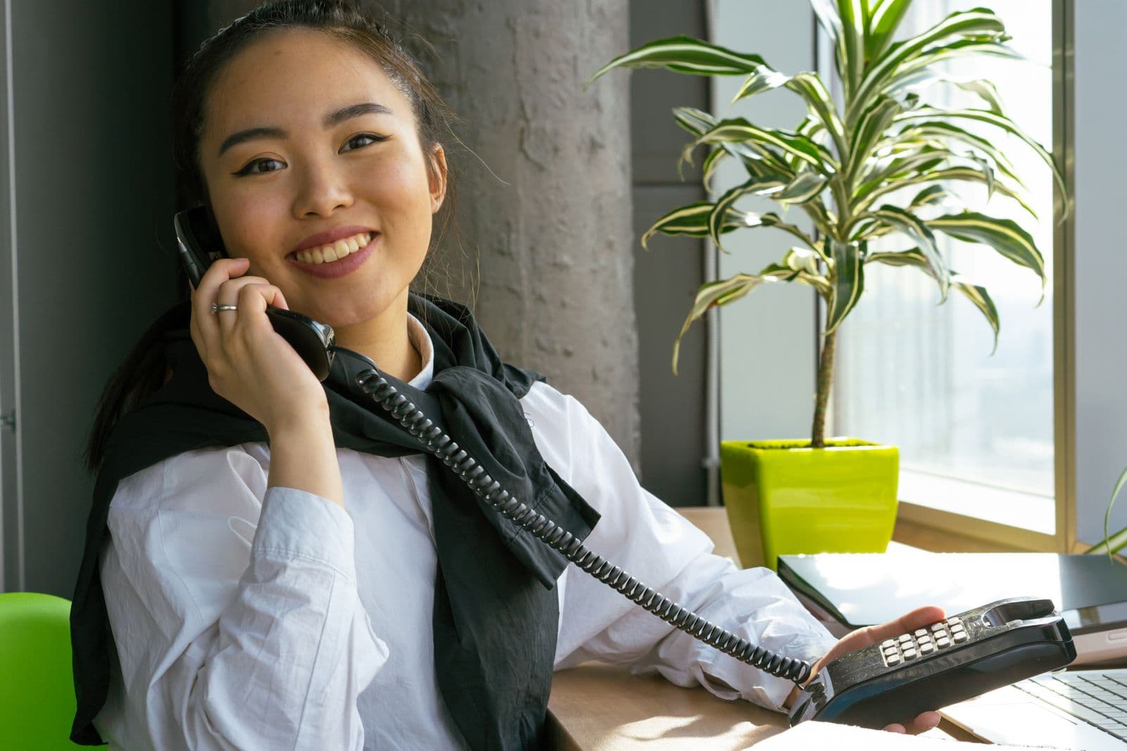 Woman smiling while answering a phone call in a bright office